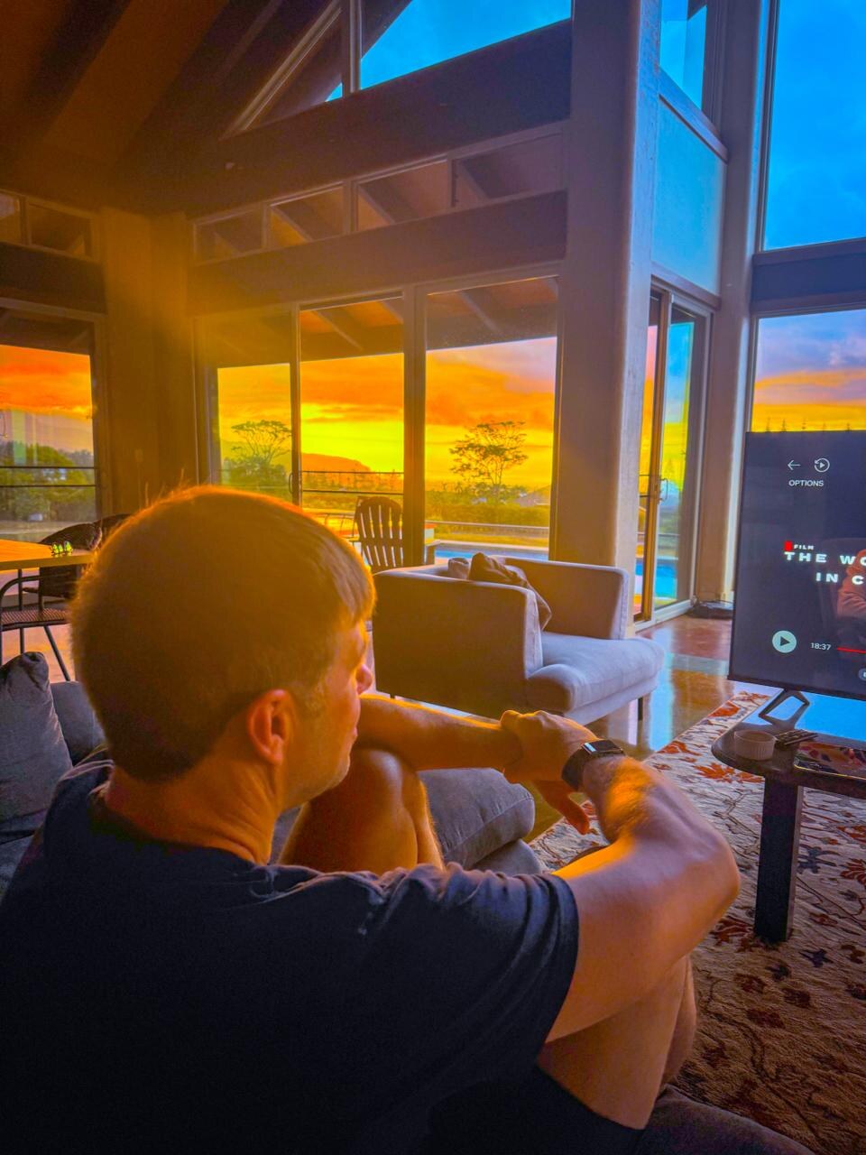Clay Collins at home, watching a blazing sunset through the windows